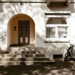 A charming urban scene in Kassel, Germany featuring a moped parked near a classic residential entrance with arched doorway.