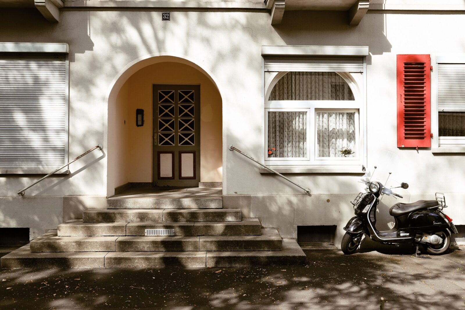 A charming urban scene in Kassel, Germany featuring a moped parked near a classic residential entrance with arched doorway.
